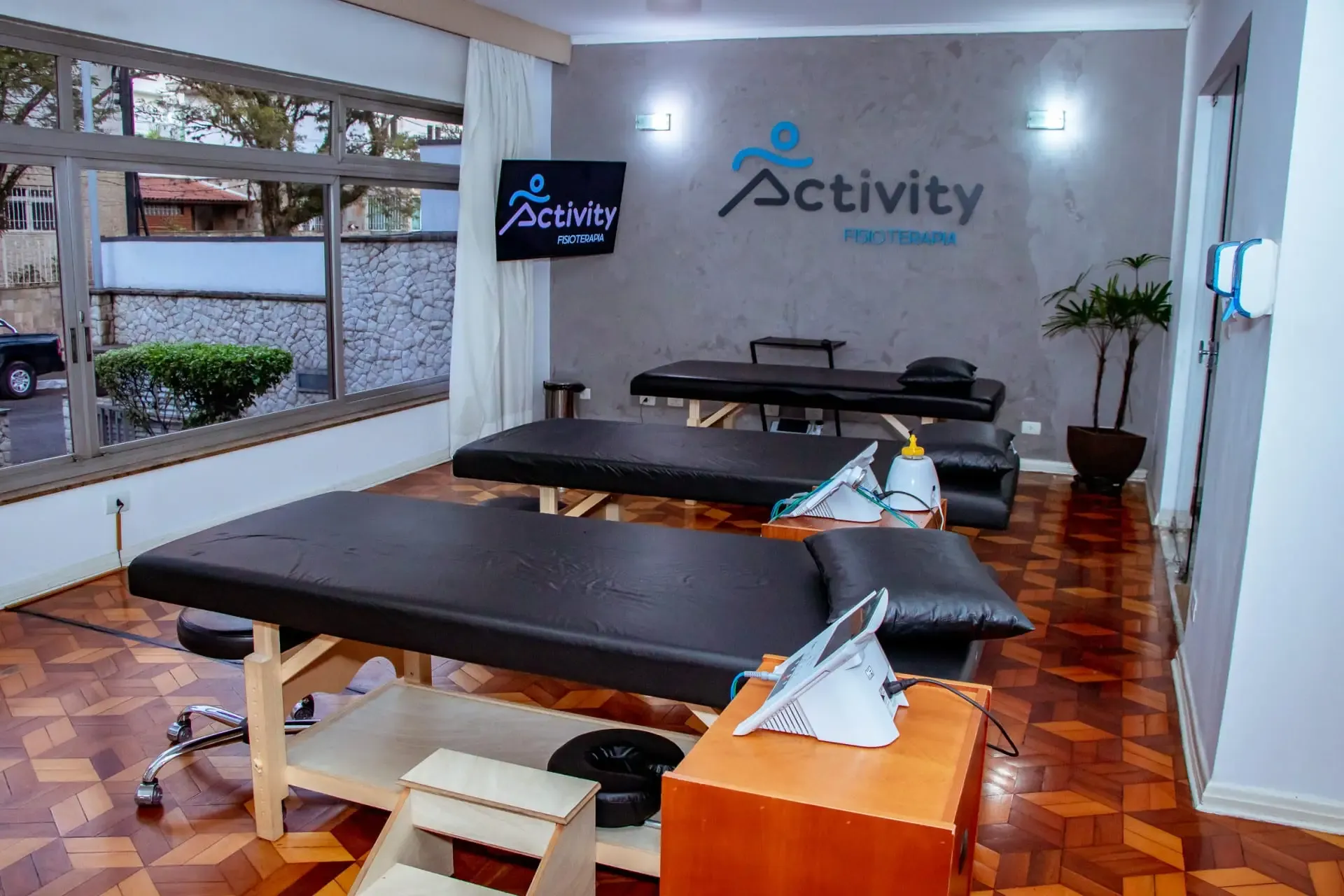 Sala de atendimento com macas, aparelhos e o logo da Activity