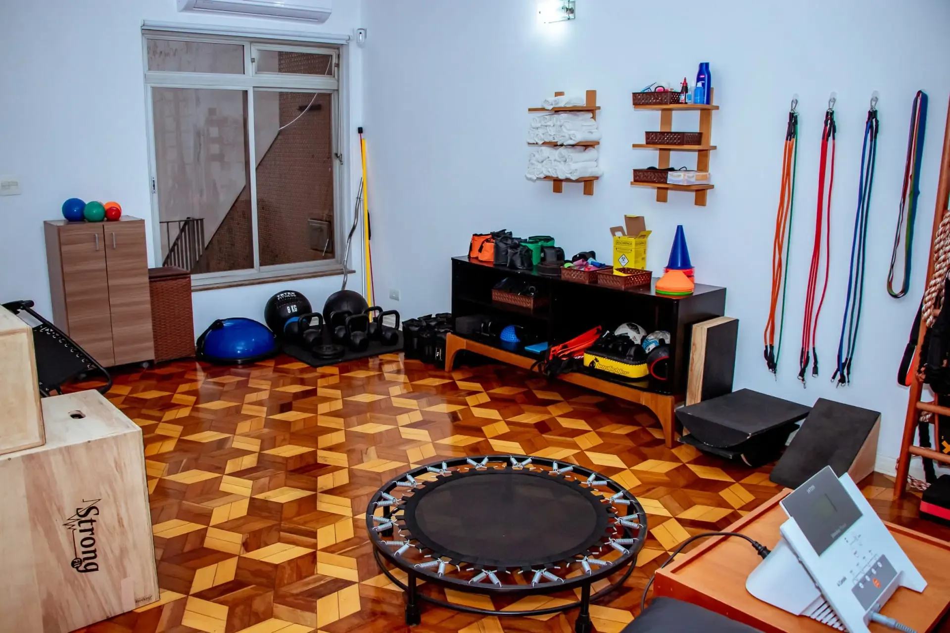Sala de exercícios com cama elástica, bolas, pesos e cones