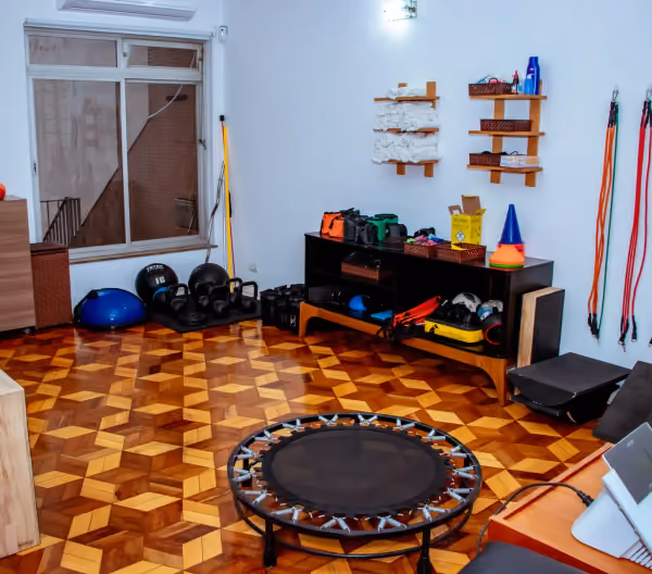 Sala de exercícios com cama elástica, bolas, pesos e cones